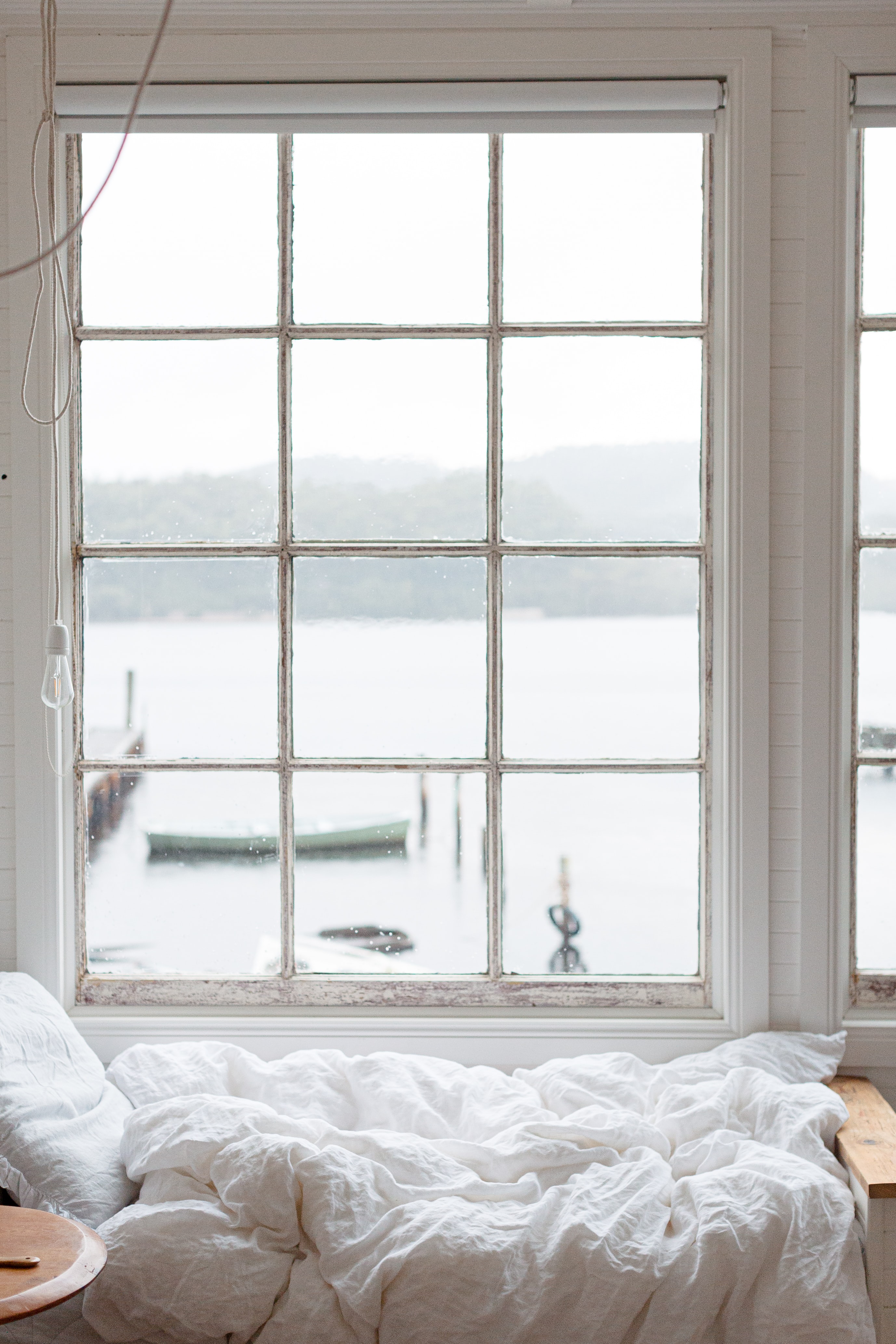 Clean white bed next to a window overlooking a harbour